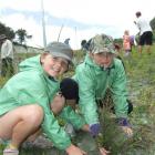 Brooke Bennett (9) and Annie Black (9), both of Kelvin Heights, plant native shrubs and grasses...