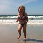 Isabelle Burton (3) runs from the waves at Karitane Beach, while her brother Maxwell (8) plays in...