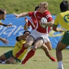 Canada's John Moonlight, centre, drives toward the try line against Brazil during a sevens match...