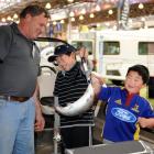Canterbury Sports Fishing Club's Ray Eade watches as James (10) and Jacob Yee (5) hold a live...