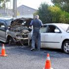A Dunedin police photographer records the damage to two vehicles whose interiors were burned out...