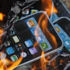 Cardboard cutouts resembling iPhones are sent on fire by labor activists near the Foxconn office...