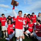 Caversham captain Tim Horner holds the premier league trophy, surrounded by victorious team-mates...