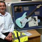 Charity auction organiser Chris Campbell, of Queenstown, with a Fender electric guitar signed by...