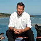 Chris Knight, flanked by dogs Basil (left) and Sybil,  is considering moving from Taieri Mouth...