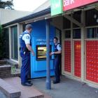 Constables Karl O'Dowda (left) and Ben Catchpole inspect the scene of a burglary at an ATM in...