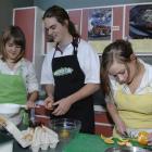 Casey Broad, Declan Smith and Gina Manning bake a cake in the Logan Park High School food...