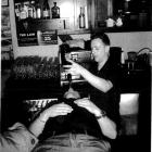 Craft Bar duty manager Michael Campbell pours liqueur from a  bottle into the mouth of a patron,...