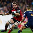 Crusaders flanker Richie McCaw runs at Highlanders halfback Aaron Smith. (Photo by Martin Hunter...