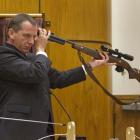 Defence witness Philip Boyce holds a rifle as suggested by a previous witness during a...