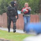 Detective Constable Rebecca Hill emerges from a Forester Ave home clutching a young baby at the...