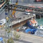 Divers stand on top of a Port Otago barge which was lifted by a crane yesterday morning after it...