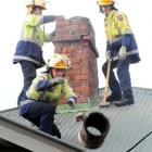 Dunedin firefighter Chris Kennett throws a chimney pot off a roof in Avonside yesterday as Simon...