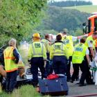 Emergency personnel treat a woman on a stretcher (at right) while the other heavily bandaged...