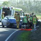 Emergency services staff work to free an elderly man from a car after a two-vehicle crash on...