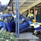 Emergency services workers work to help a woman who was injured when the car she was driving...