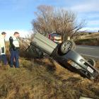 Emergency staff inspect the wreckage of a car which hit black ice and rolled on State Highway 85...