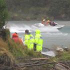 Emergency workers help the crew of a jet-boat which flipped at the confluence of the Shotover and...