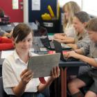 Emily Paine (12) completes some school work using her own digital device with fellow classmates ...