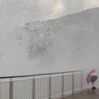 Emily Parker-Bardrick (13) gets limited protection under her umbrella from huge seas at the...
