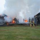 Fire crews dampen down the smoking remains of the homestead on Sunday. Photo by Tracey Roxburgh.