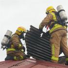 Fire crews remove roofing to ventilate a house after it caught fire  in Milton yesterday.  Photo...