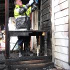 Fire safety officer Barry Gibson checks the wiring at a badly damaged house in Millers Flat after...