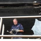 Fire Service fire safety officer Barry Gibson examines the evidence inside the charred ruins of a...