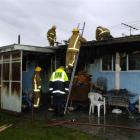 Firefighters (above) remove roofing iron to access hot spots after fire broke out at Andrew and...