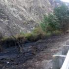 Firefighters and a helicopter with a monsoon bucket dampen  hot spots following a large...