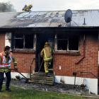 Firefighters  begin dampening down hot spots following a house fire on Glen Rd, Mornington. Photo...
