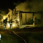 Firefighters dampen down a fire that gutted an Aramoana house early yesterday. Photo by Stacey...