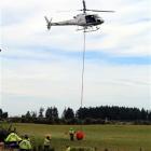 Firefighters fill a helicopter monsoon bucket with water pumped from a nearby small creek during...