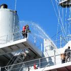 Firefighters pour water on an imaginary fire on board HMNZS Endeavour during an exercise in...