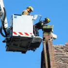 Firefighters remove loose bricks from the top of a heritage building inside the central...