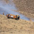 Firefighters spray water on one section of a  the grass fire near Tarras yesterday.Photos by...