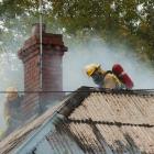 Firefighters strip iron from the roof of a burning house in Chambers St, Northeast Valley, on...