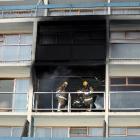 Firefighters with breathing apparatus check the room where a fire broke out on the third floor of...