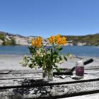 Flowers and a candle on a picnic table with the Blue Lake in the background. Photo by Staff...