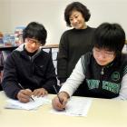Francesca Shin assists Korean students Lee Deokjae (25), left, and Nick Yu (15) with opening bank...