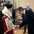 Greek Prime Minister Antonis Samaras (R) bows in front of Greece's Orthodox Archbishop Ieronymos...