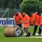 Ground staff work to remove water from around the covers as rain continues to fall yesterday...