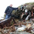 Hampden resident Bent Jansen examines rubbish exposed by coastal erosion of the Hampden dump....