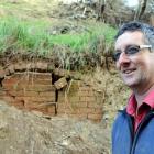 Henley farmer James Adam in front of the hidden stucture which was uncovered by a recent landslip...