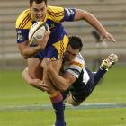 Highlanders fullback Israel Dagg is tackled by Brumbies midfield back Adam Ashley-Cooper in the...