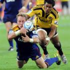 Highlanders halfback Jimmy Cowan grabs the loose ball under pressure from Hurricanes replacement...