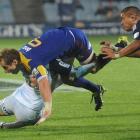 Highlanders halfback  Jimmy Cowan is tackled by a Blues defender (obscured) while Blues hooker...