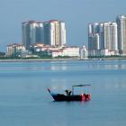 Ignoring the high-rise buildings, a Penang fisherman checks his night's catch. Photos by Gillian...