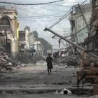 In this January 20, 2010 file photo, a woman walks down a devastated street in Port-au-Prince,...