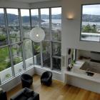 Interior living spaces are organised to make the most of the harbour view. This photo is taken...